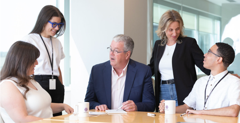 BOYNECLARKE colleagues meet at a conference table, talking and reviewing notes together.