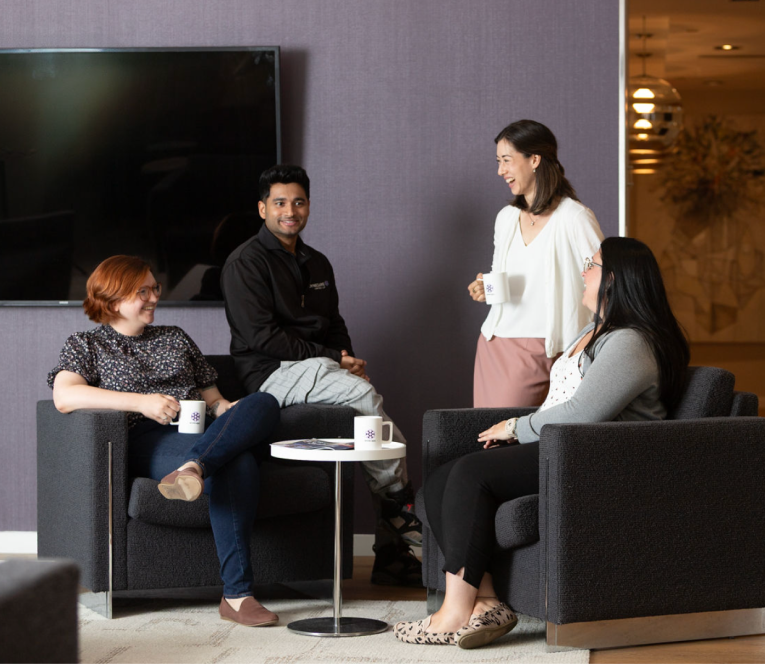 BOYNECLARKE colleagues sit and stand together in a lounge area, talking and sharing coffee.