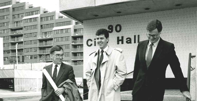 Three BOYNECLARKE colleagues walk down the steps of City Hall in a historic black-and-white photo.